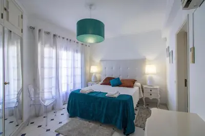a white bedroom with a bed and a green lamp at Villa Brisa do Mar in Galé