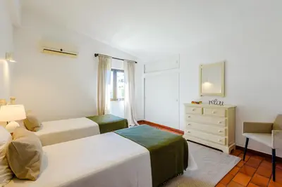 a bedroom with two beds and a dresser and a chair at Villa Margarida - heatable pool & city center in Albufeira