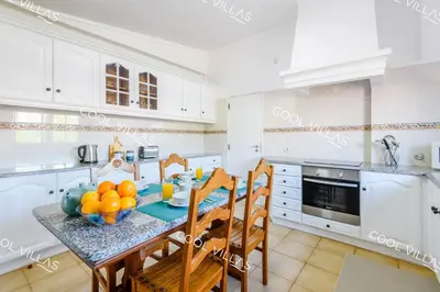 a kitchen with white cabinets and a table with fruit on it at Villa Margarida - heatable pool & city center in Albufeira