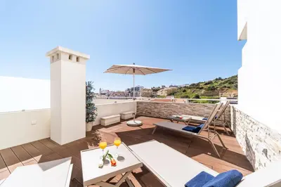 a balcony with a patio furniture and an umbrella at Histórical City Center Penthouse Albufeira in Albufeira