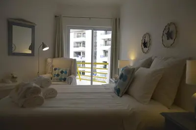 a bedroom with a large white bed with towels on it at Apartamento próximo da Marina Vilamoura c/piscina e estacionamento in Vilamoura