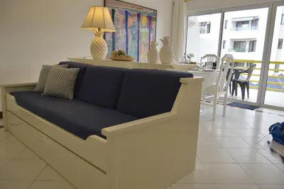 a couch in a living room with a table and chairs at Apartamento próximo da Marina Vilamoura c/piscina e estacionamento in Vilamoura