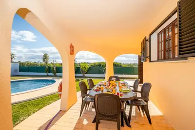 a table and chairs on a patio with a pool at Villa Ushuaia by Algarve Vacation in Guia