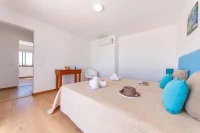 a white room with a bed with blue pillows at Villa Abel by Algarve Vacation in Albufeira