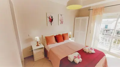 a bedroom with a bed with orange pillows and a window at 3 bedroom apartment in Oura Albufeira with amazing pool at walking distance to beach, strip and old town, WIFI and AC, private condo in Albufeira