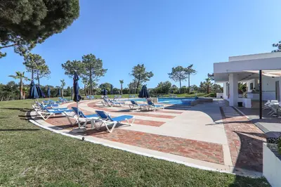 a group of chairs and umbrellas next to a pool at Apartment Dansk in Almancil