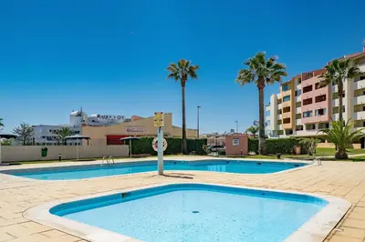 a large swimming pool with palm trees and buildings at LovelyStay - Bela Vista 3BDR Duplex Penthouse with Pool in Albufeira