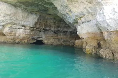 a cave in a cliff with blue water at Aparto Golf in Guia