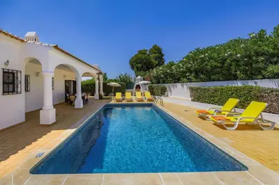 a swimming pool with chairs and a house at Villa Aldeia by Villa Plus in Albufeira