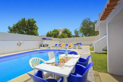 a white table and chairs next to a swimming pool at Villa Altis Park by Villa Plus in Albufeira