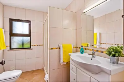 a bathroom with a sink and a toilet and a window at Villa Emilio Pequena by Villa Plus in Albufeira