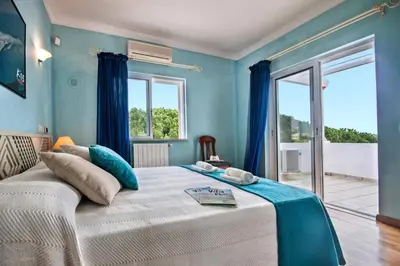 a bedroom with a large bed with blue walls at Villa Rosa by Villa Plus in Olhos de Água
