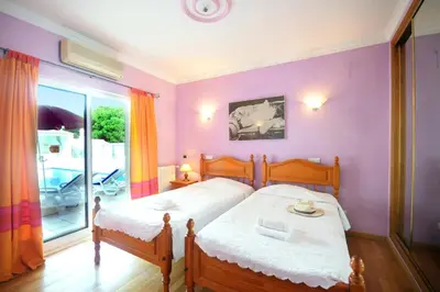 a bedroom with two beds and a purple wall at Villa Rosa by Villa Plus in Olhos de Água
