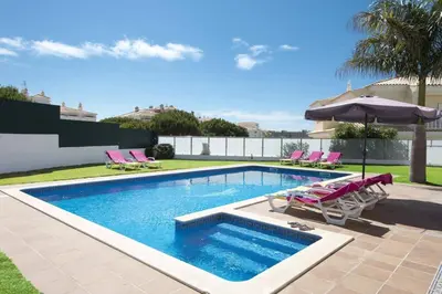 a swimming pool with chairs and an umbrella at Villa Soni by Villa Plus in Olhos de Água