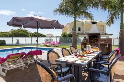 a patio with a table and chairs and a fireplace at Villa Soni by Villa Plus in Olhos de Água