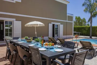 a patio with a table and chairs and a pool at Villa Teotel by Villa Plus in Almancil