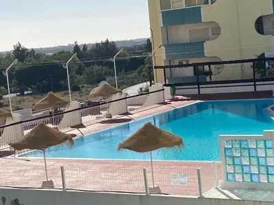 a swimming pool with straw umbrellas on top of a hotel at House Amendoeiras , Vila moura in Vilamoura