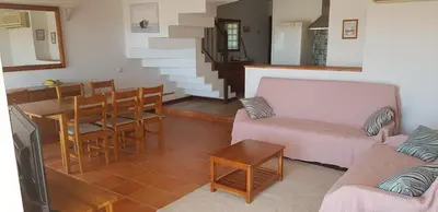 a living room with a couch and a table and chairs at New Grand duplex avec terrasse plein sud vue piscine in Vilamoura