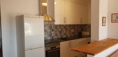 a kitchen with white cabinets and a wooden table at New Grand duplex avec terrasse plein sud vue piscine in Vilamoura