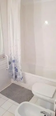 a white bathroom with a toilet and a shower at New Grand duplex avec terrasse plein sud vue piscine in Vilamoura