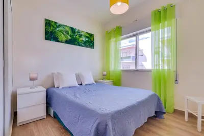 a bedroom with a bed and a window with green curtains at Quarteira 2Br - near the beach at Homesbyfc in Quarteira