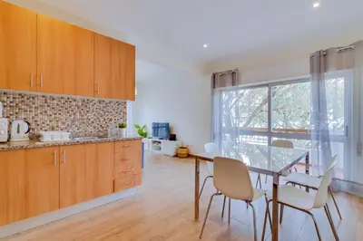 a kitchen with wooden cabinets and a table and chairs at Quarteira 2Br - near the beach at Homesbyfc in Quarteira