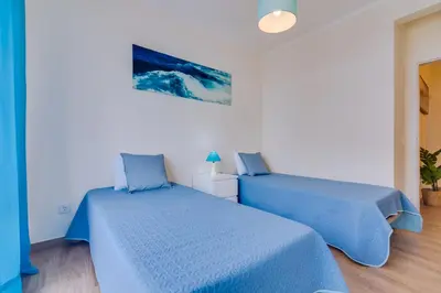 two beds in a white room with blue sheets at Quarteira 2Br - near the beach at Homesbyfc in Quarteira