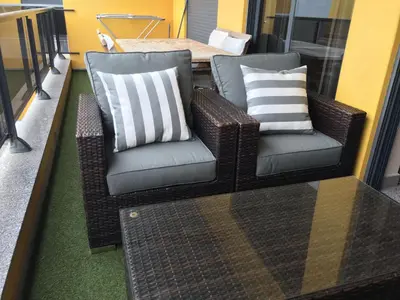 two wicker chairs and pillows on a balcony at Apartamento frente ao mar com piscina de água salgada in Quarteira