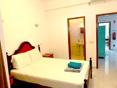 a bedroom with a bed and a bathroom at The Central Guesthouse in Faro