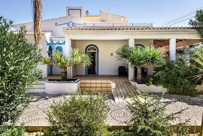 a white house with palm trees in front of it at Villa Cabrita, Superb location, large villa, walk to restaurants, supermarkets beach in Guia