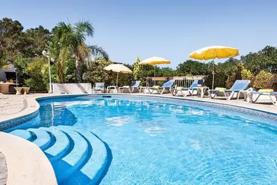 a large swimming pool with chairs and umbrellas at Villa Cabrita, Superb location, large villa, walk to restaurants, supermarkets beach in Guia