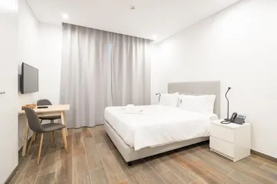 a bedroom with a bed and a desk and a tv at Roots Hotel in Faro