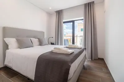 a bedroom with a bed with white sheets and a window at Roots Hotel in Faro