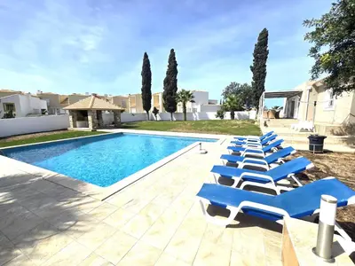 a row of blue lounge chairs next to a swimming pool at Villa Sunshine - Albufeira in Albufeira