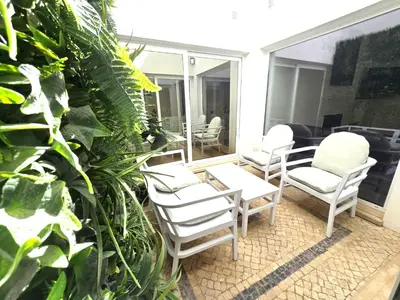 a patio with white chairs and a table and some plants at Villa Sunshine - Albufeira in Albufeira