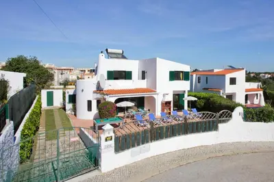 a large white house with chairs and umbrellas at Villa Lilly by Villa Plus in Albufeira