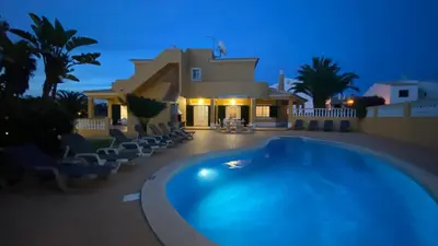 a villa with a swimming pool in front of a house at Villa Rafaela com piscina Albufeira in Albufeira
