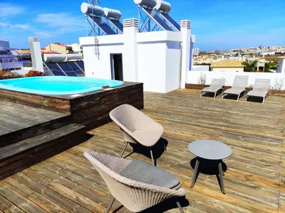 a deck with chairs and a table and a pool at Apartamento Rooftop Montenegro in Faro