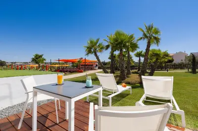 a table and chairs on a patio with palm trees at Regency Salgados Hotel & Spa in Albufeira