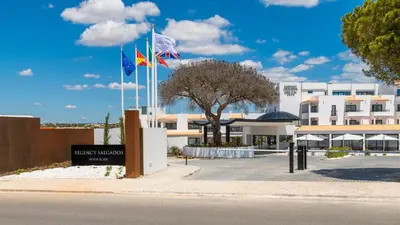 a hotel with three flags in front of a building at Regency Salgados Hotel & Spa in Albufeira