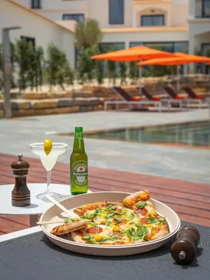 a plate of pizza on a table with a bottle of beer at Regency Salgados Hotel & Spa in Albufeira