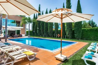 a swimming pool with chairs and umbrellas next to a pool at Villa Laguna, Golf - Stunning house - Laguna Golf Course in Quarteira