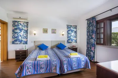 a bedroom with a bed with blue sheets and blue curtains at Villa Elanor by Villa Plus in Albufeira