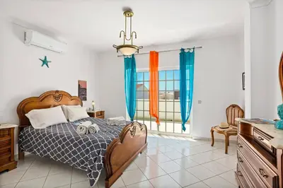 a bedroom with a large bed with blue curtains at Villa Hope by Villa Plus in Galé