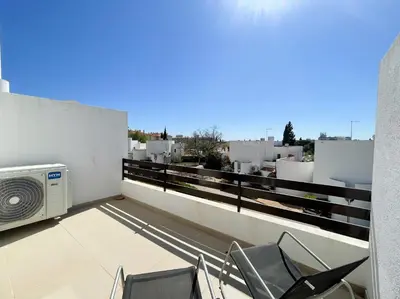 a balcony with a microwave and chairs on a roof at Casa Rosa - Vilamoura in Vilamoura