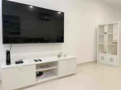 a white entertainment center with a large television on a wall at Casa Rosa - Vilamoura in Vilamoura