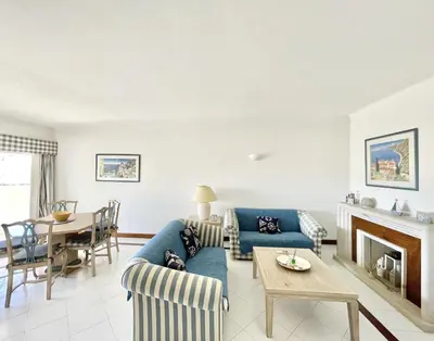 a living room with a blue couch and a table at Alcharb - Pool & City Center - Vilamoura in Quarteira