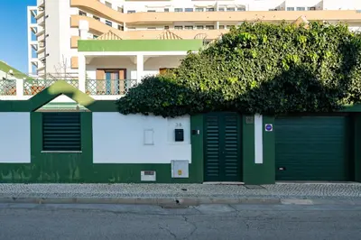 a green and white wall with a tree on top of it at Holiday villa in elite residential area of Faro in Faro