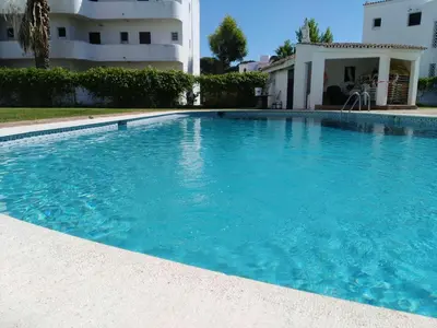 a large blue swimming pool in front of a building at Garden View Vilamoura Apartment in Vilamoura