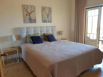 a bedroom with a large white bed with blue pillows at Oura Beach T1 apartment Coral , close to the Strip, Swimming Pool, Wi Fi, A/C in Albufeira